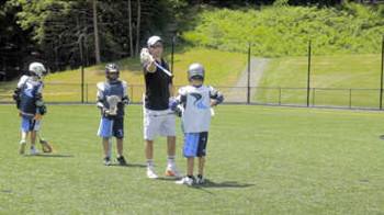 A coach instructing a lacrosse player