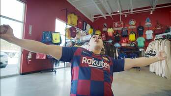 A man in a soccer jersey celebrating a goal in a store