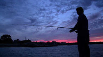 Silhouette of a man fishing at sundown